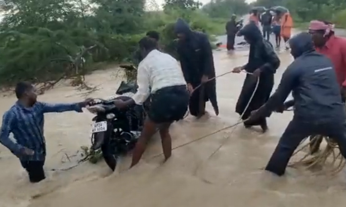  Locals Rescued Young Man Who Was Washed Away With Bike In Flood Water Details, V-TeluguStop.com